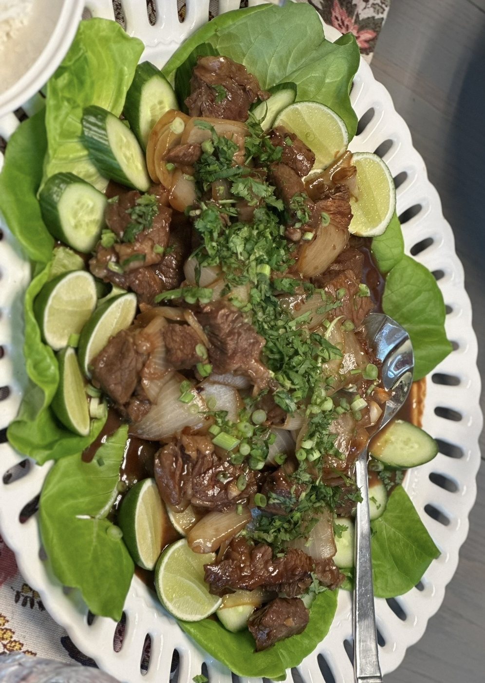 Sautéed beef and onions on lettuce with cucumber and lime on an oval platter