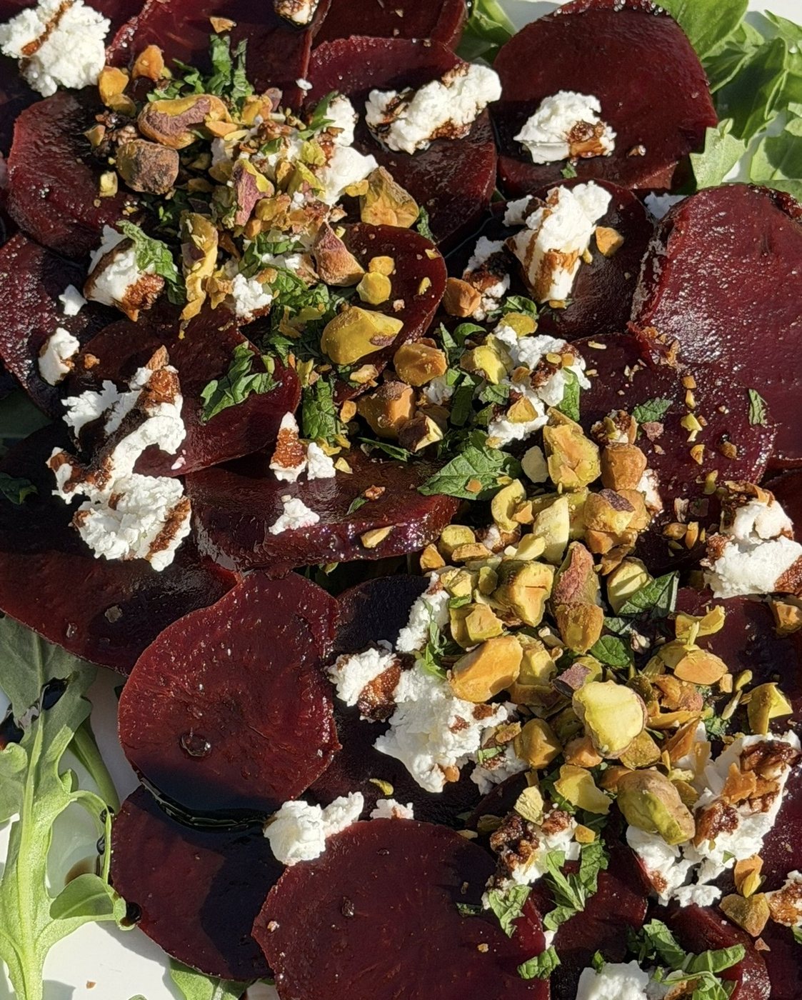 Sliced beet salad with crumbled cheese and crushed pistachios